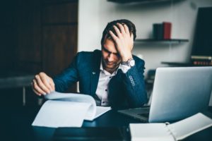 Business Owner Sitting at Desk with Hand On Head