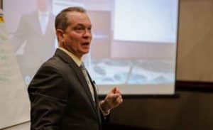 Ken Kilday presents in front of a projected screen on business organizational systems