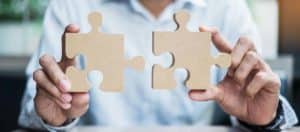 man connects puzzle pieces representing the connection of values, purpose, and vision to create a mission statement