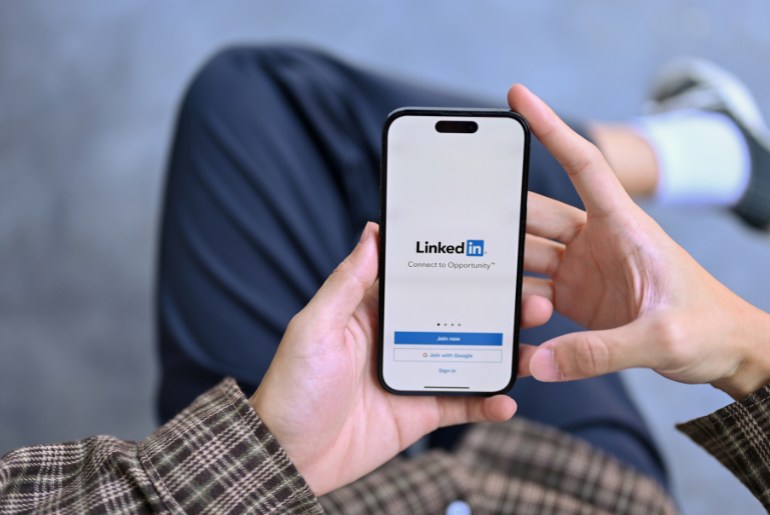 man looking at phone with linkedin on the screen