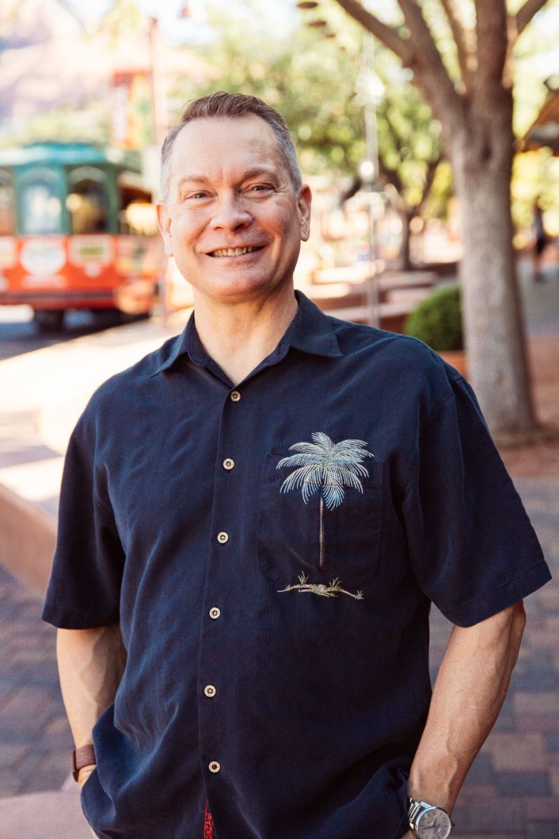 Ken wearing a casual shirt standing in Sedona in front of the Trolley.