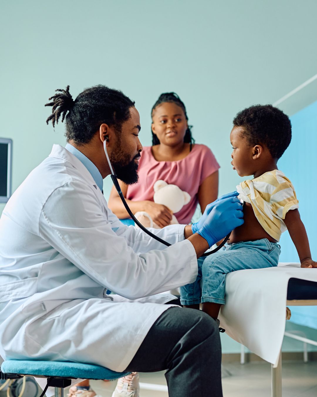 image of doctor listening to a little boys heart with mom watching