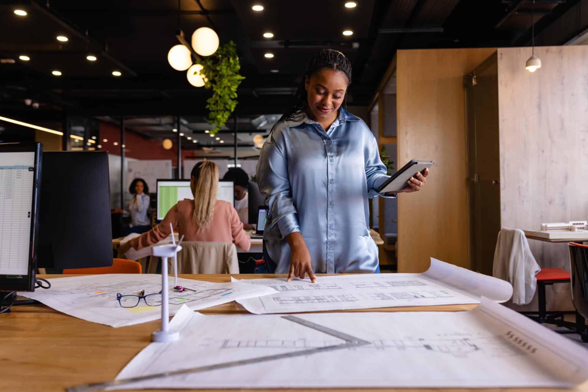 happy-plus-size-african-american-female-architect looking at plans on a table