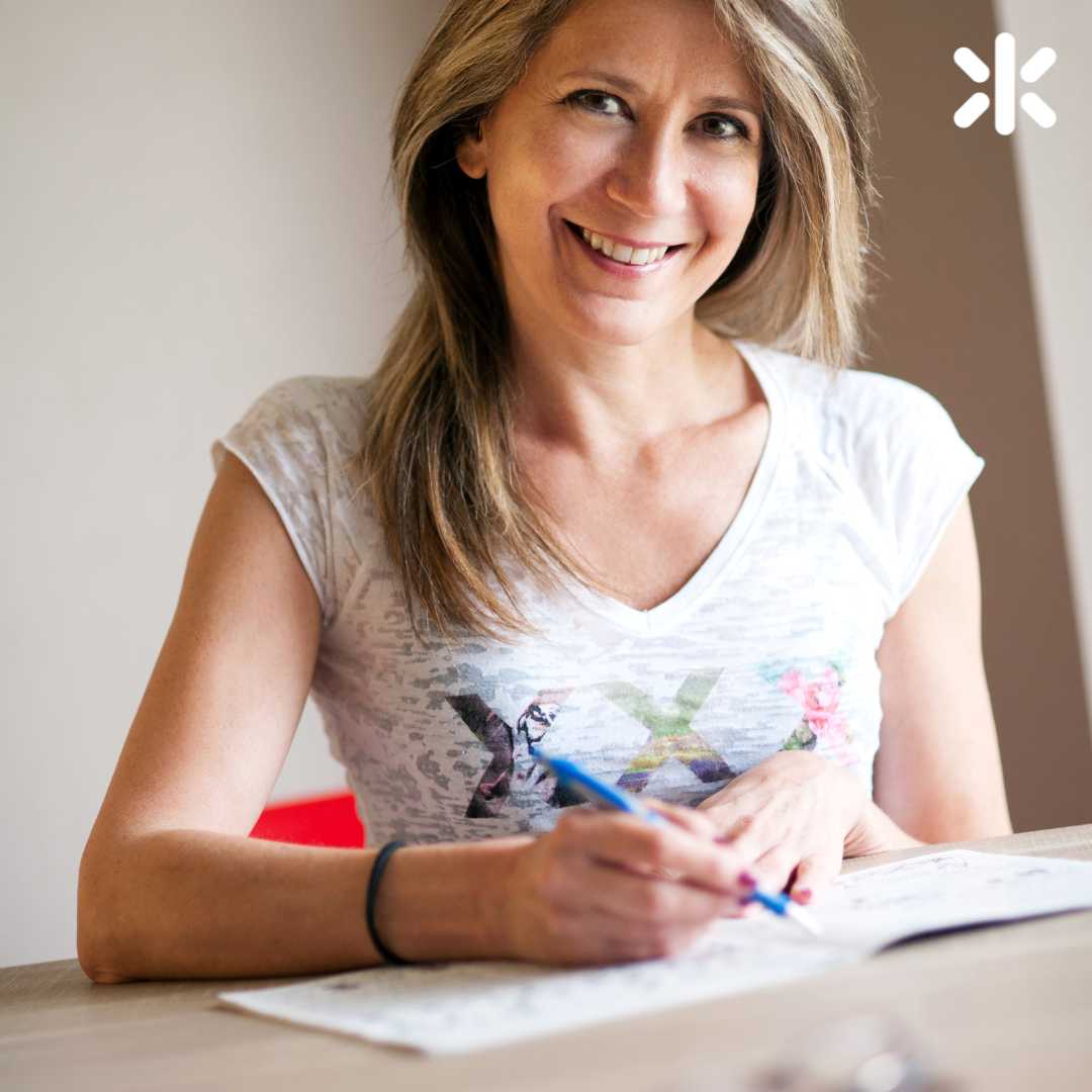 female smiling at the camera sitting at a desk