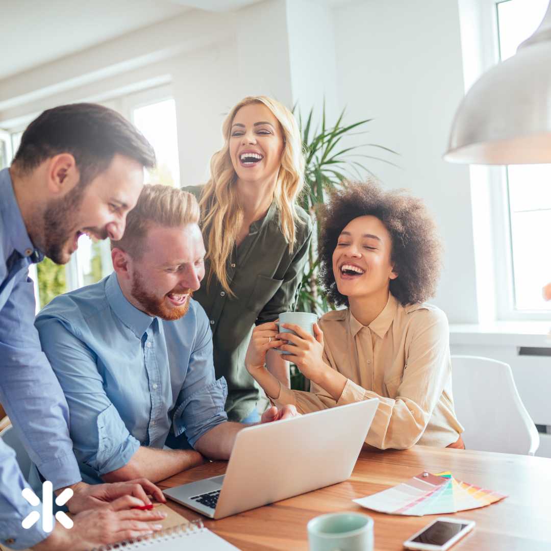 group of coworkers looking at a computer and laughing