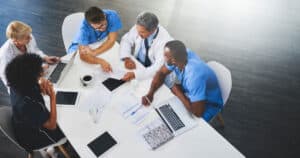 Medical team sitting around white table having meeting