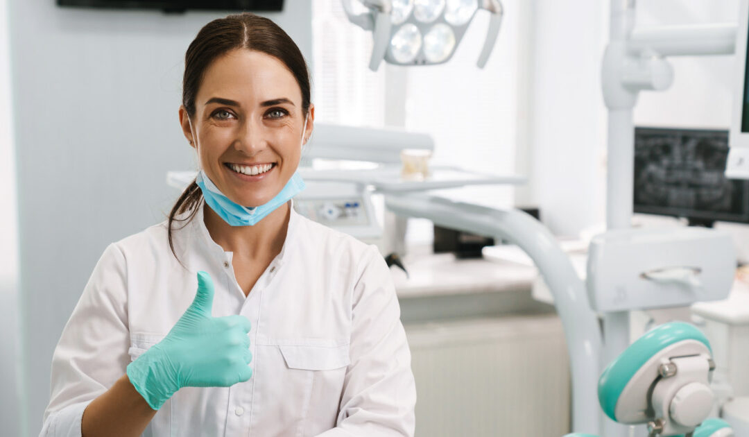 Dentist sitting is examination room giving thumbs up