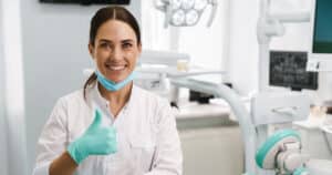 Dentist sitting is examination room giving thumbs up