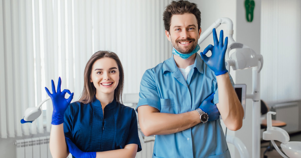 Dentist and dental hygienist smiling and giving okay sign