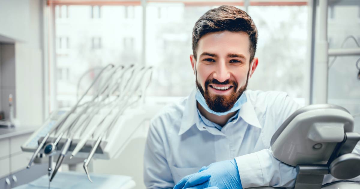 Young male dentist wearing PPE and standing in operating room