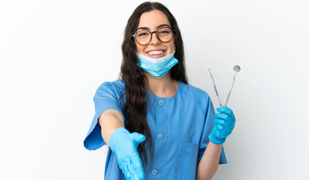 Dentist holding dental tools and extending her hand out to meet new patient
