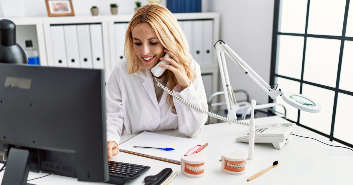 Dental office manager working in her office and reaching out to patients