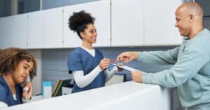Dentist office receptionist providing new patient form to a man