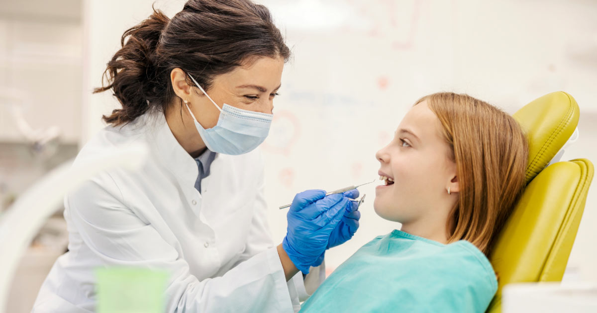 Dentist smiling while trying to put young patient in chair at ease