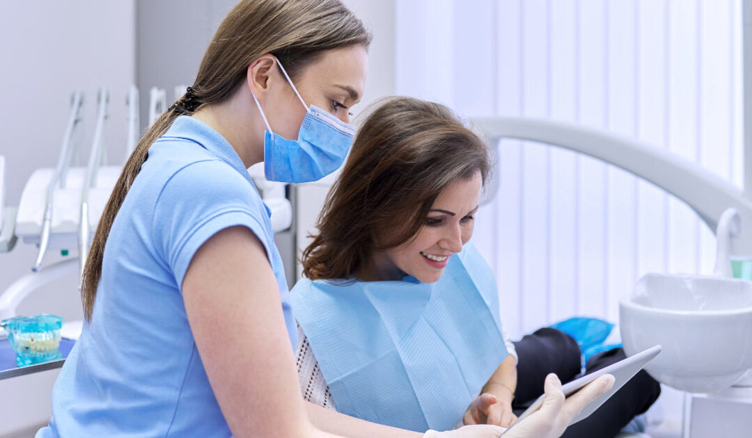 Dental professional reviewing paperwork digitally with patient