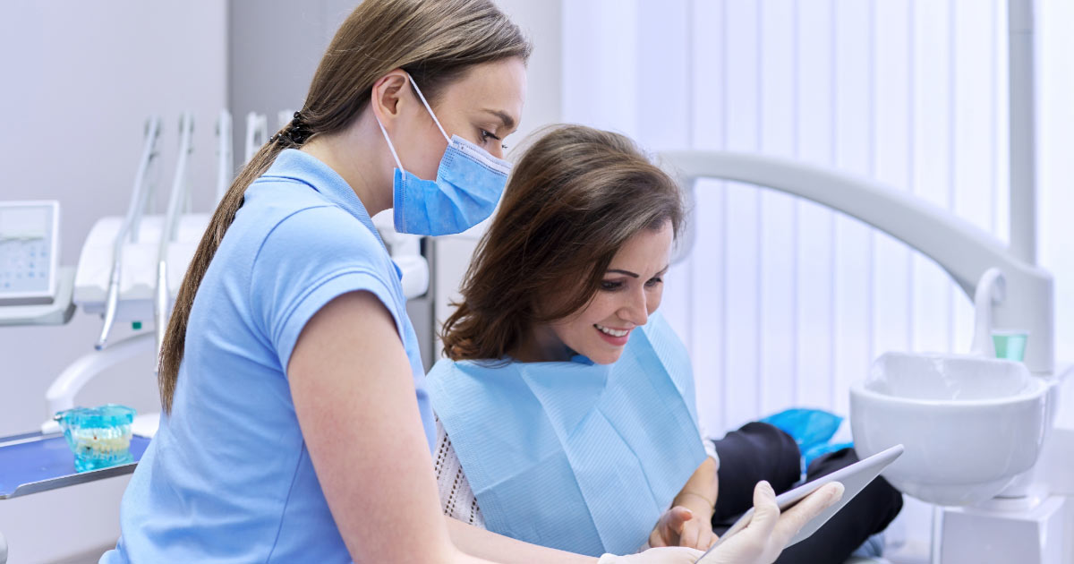 Dental professional reviewing paperwork digitally with patient