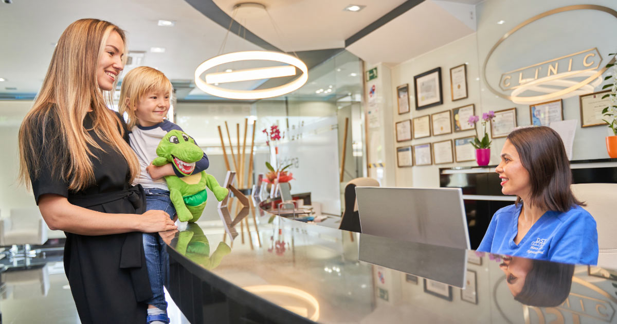 Mom holding her young child while checking in at her dentist office