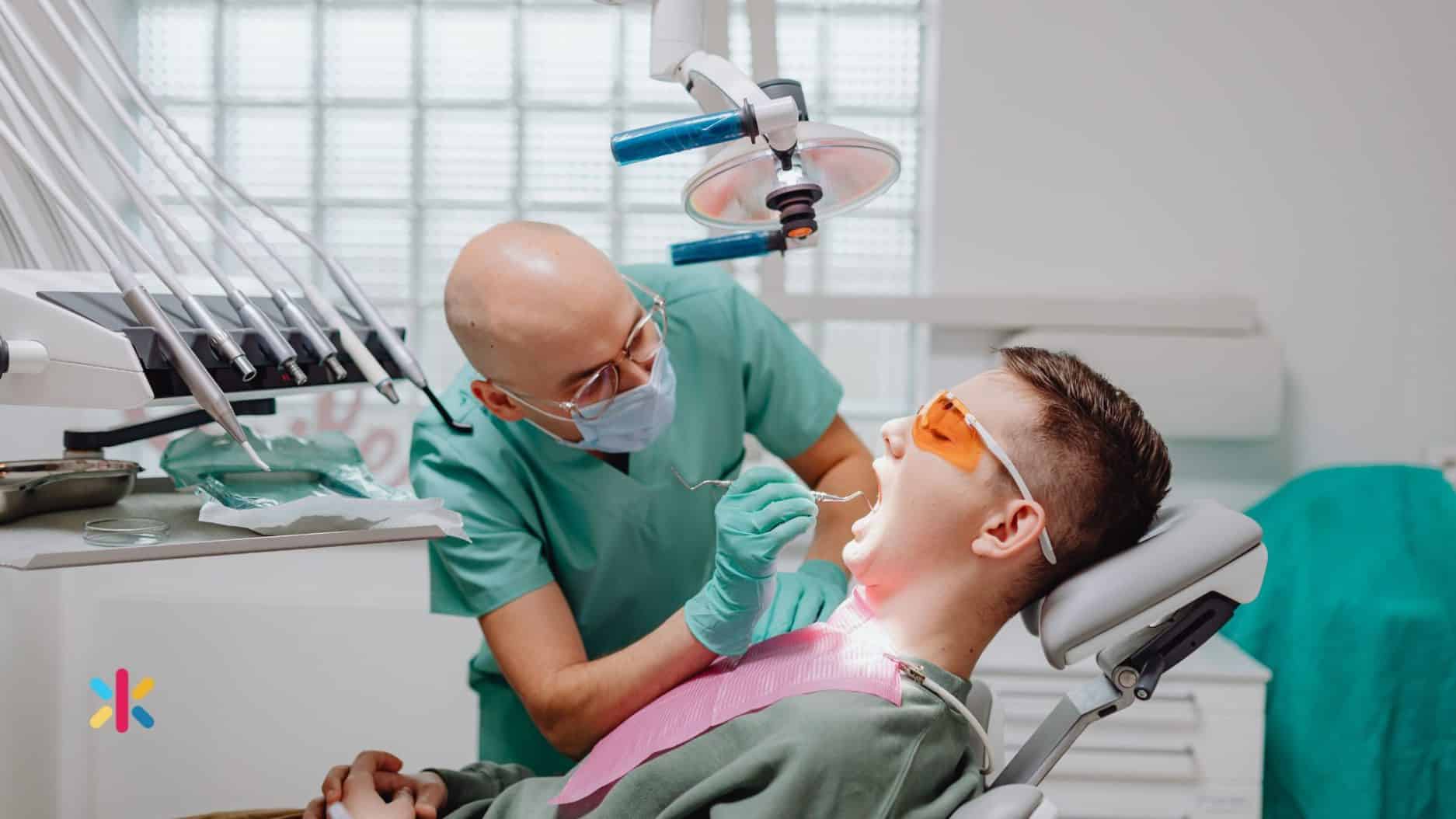 Dentist examining a young patient’s teeth using dental tools in a bright and modern dental office