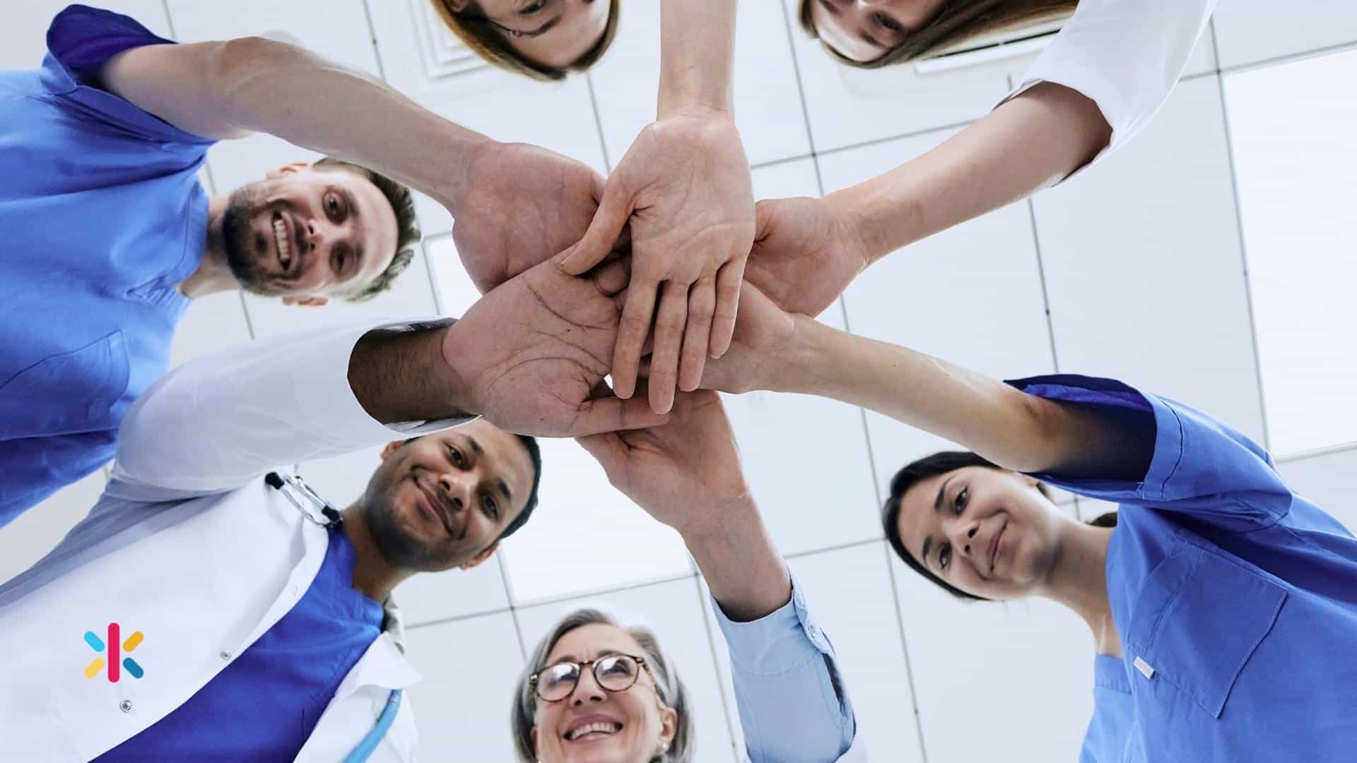 Dental professionals stacking hands together symbolizing teamwork, collaboration, and strong dental practice culture.